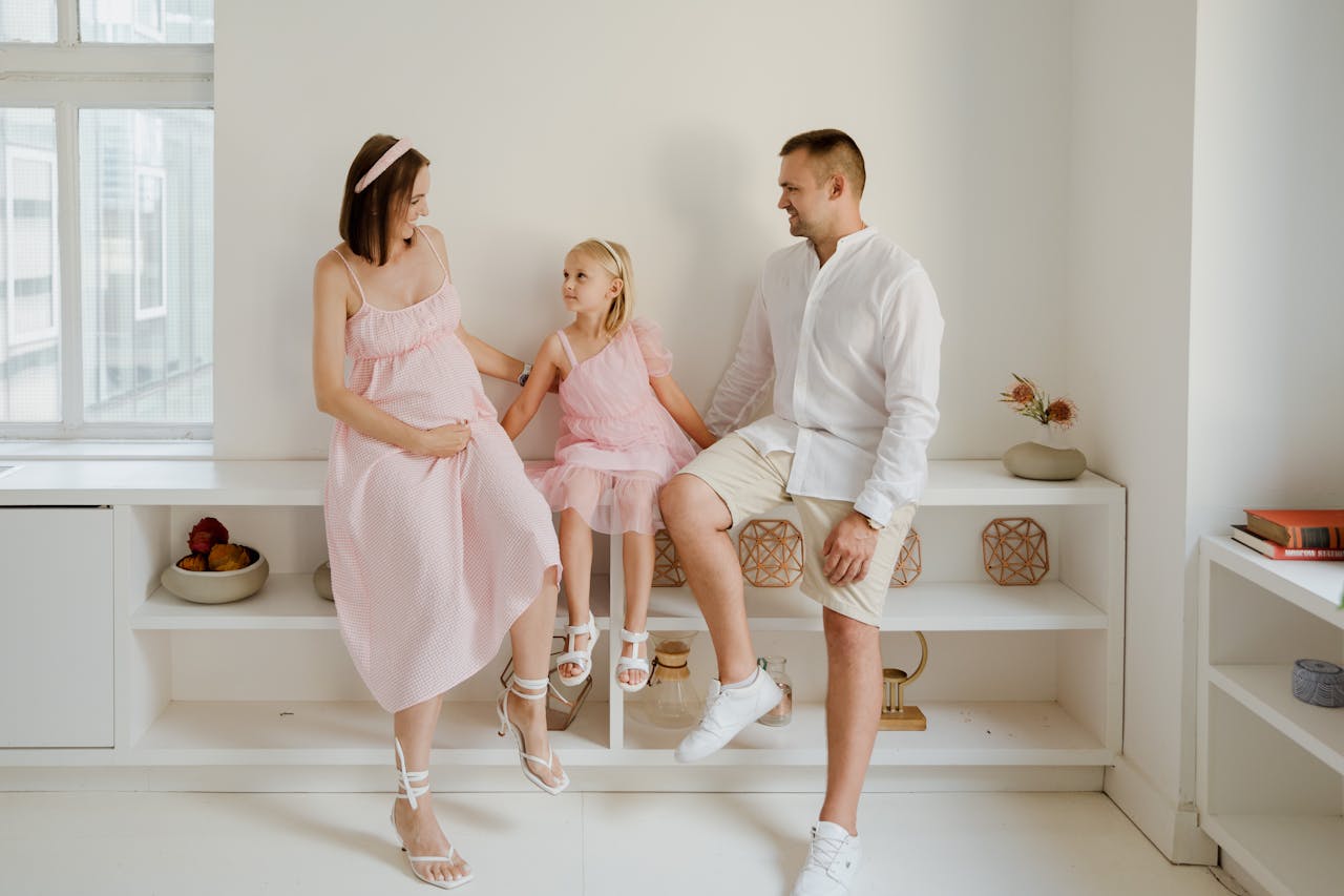 A joyful family of three sitting together indoors with smiles and warmth.